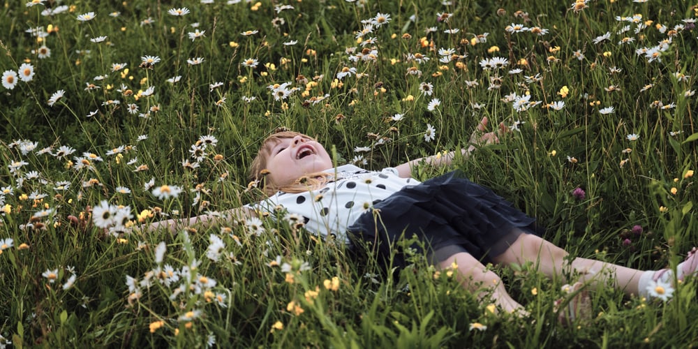 Kind liegt in bunter Blütenpracht